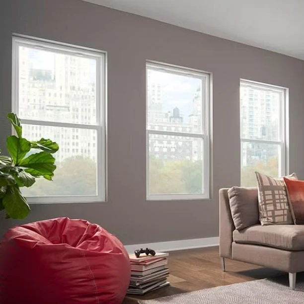 Bright living room with large white-framed windows allowing abundant natural sunlight