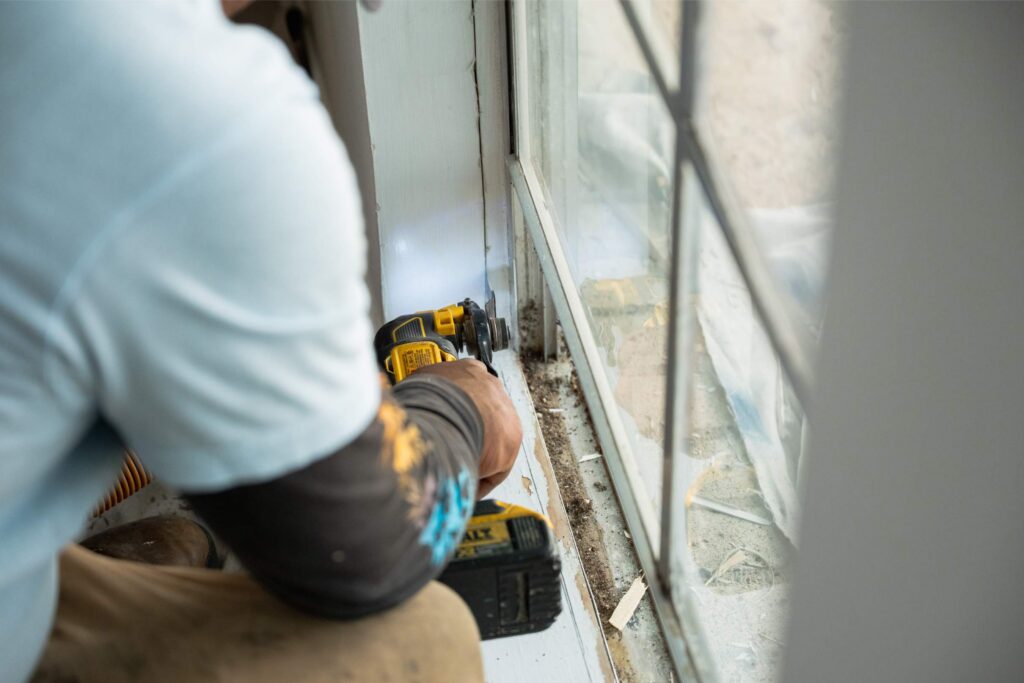 Professional crew completing a house window replacement by removing old windows and installing new replacement windows.